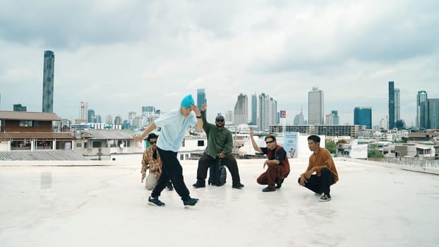 Professional break dance team practice B-boy dance while multicultural friends at rooftop. Young modern dancing group doing hip hop movement. Style,fashion,action. Outdoor sport 2024. Endeavor.