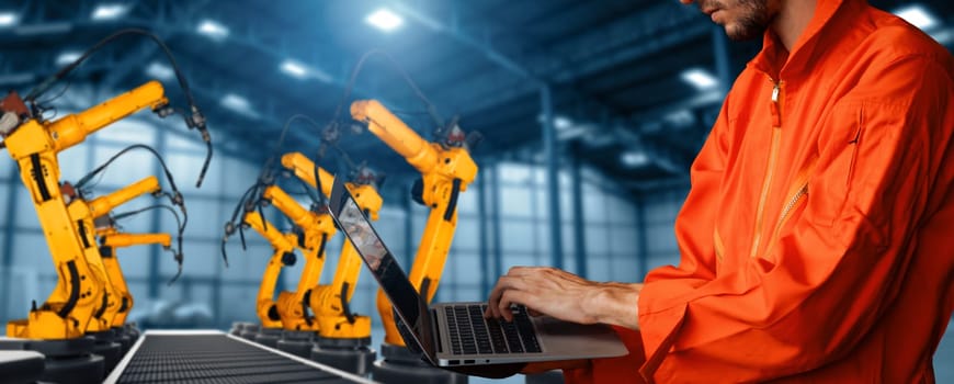 MLP Engineer use advanced robotic software to control industry robot arm in factory. Automation manufacturing process controlled by specialist using IOT software connected to internet network.