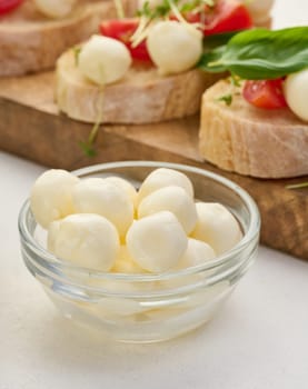 Mozzarella balls in glass bowl on a white background, close up