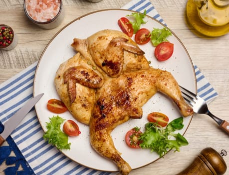 Whole fried chicken with spices in a white round plate on the table, top view