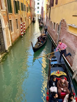 Italy, Venice, April 25, 2024, Gondoliers on gondolas carry tourists. High quality photo
