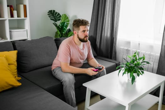 Man playing videogames in living room sitting on sofa