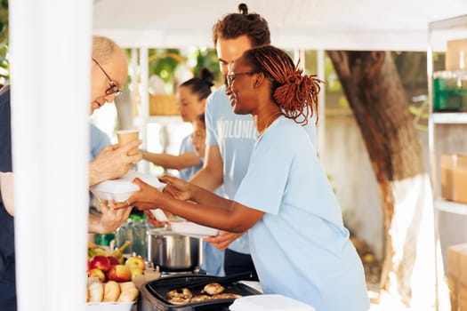 Multiracial hunger relief team provides free meals and assistance at local center, supporting the needy and homeless. Volunteers distribute non-perishable food, sharing compassion and hope.