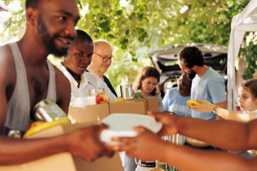 Multiethnic group of volunteers providing humanitarian aid to homeless people. They distribute meal boxes canned goods and packages with genuine smiles helping to alleviate poverty and hunger.