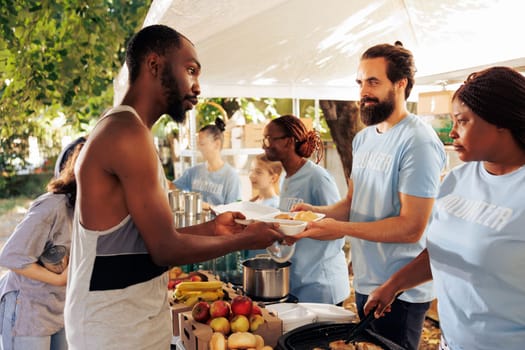 Voluntary team at food bank, providing a compassionate effort to alleviate poverty and offer humanitarian aid. Homeless, refugees, and the needy receive meals and donations from generous volunteers.