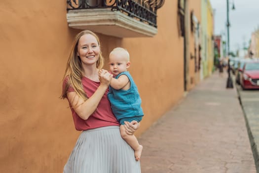 Mother and baby son tourists explore the vibrant streets of Valladolid, Mexico, immersing herself in the rich culture and colorful architecture of this charming colonial town.