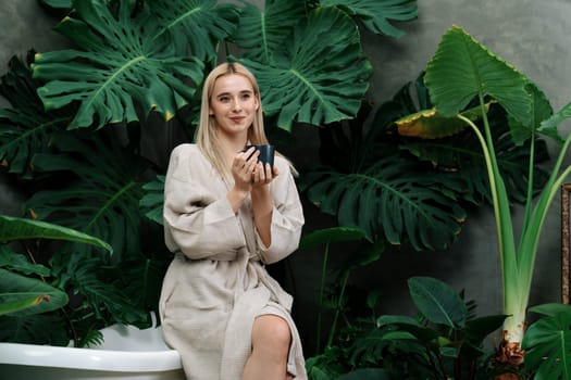 Tropical and exotic spa garden with bathtub in modern hotel or resort with young woman in bathrobe drink coffee, enjoy leisure and wellness lifestyle surround by lush greenery foliage. Blithe