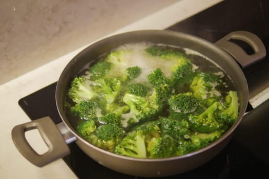 cooking broccoli in pan on electric stove ,