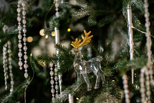 Close-up of a festively decorated outdoor Christmas tree with balls on a blurred sparkling fairy background. Defocused garland lights, bokeh effect