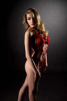 Charming blonde with curly hair posing in red negligee