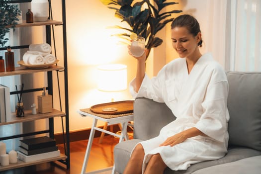 Beauty or body treatment spa salon vacation lifestyle concept with woman wearing bathrobe relaxing with drinks in luxurious hotel spa or resort room. Vacation and leisure relaxation. Quiescent