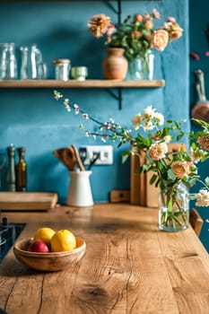 A kitchen with a wooden table and a bowl of fruit on it. The bowl contains apples and lemons. There are also vases with flowers on the table. The kitchen is clean and well-organized. Generative AI