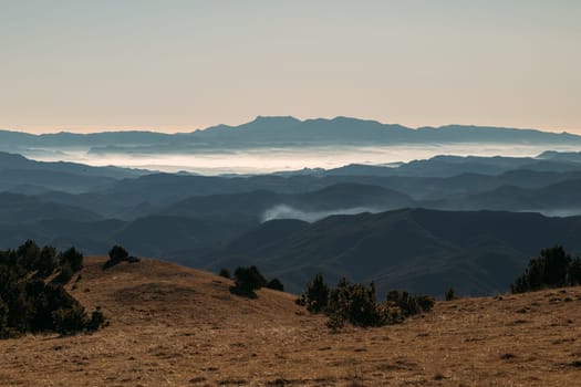 Layered hills recede into the distance, meeting a misty horizon at daybreak.