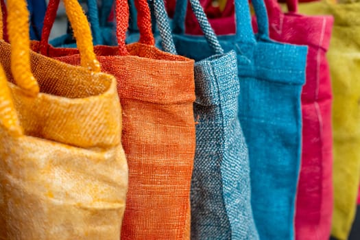 A row of colorful bags hang on a rack. The bags are of different colors and sizes, and they are all made of the same material. Generative AI