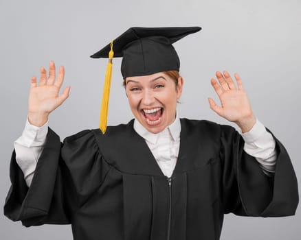 Caucasian woman dancing in graduation gown on white background
