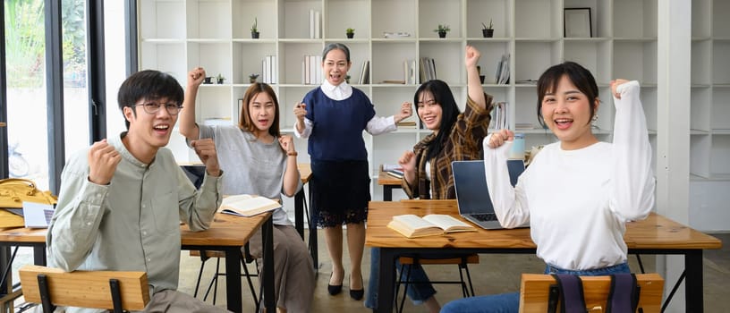 Happy university students and mature professor celebrating success in the classroom.