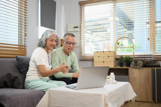 Elderly man and woman sitting in front of a laptop having an online video call with doctor. Telehealth concept.