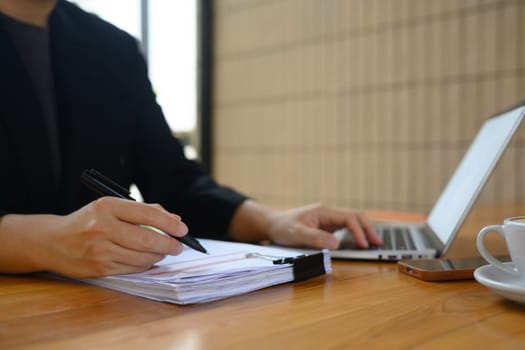 Cropped shot male entrepreneur reading document at office desk.