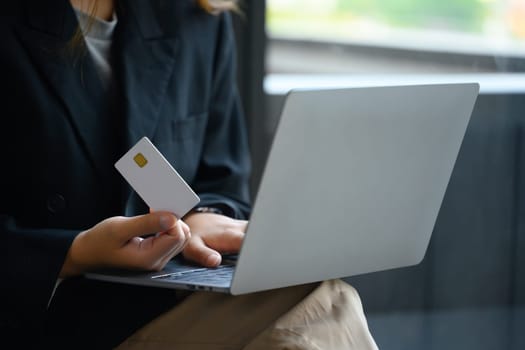 Business woman holding credit card and using laptop making payment or ordering via the internet.