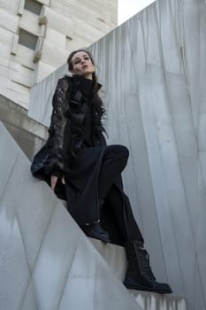 Fashion-forward woman in black textured attire posing on concrete architectural elements