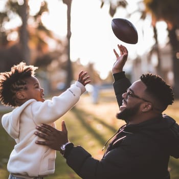 Father and son sharing a joyous moment playing football on a sunny day