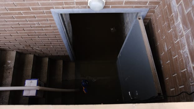 Recently flooded basement seen with a large pipe and pump used to pump out flooded basement water. The flooded basement of the house.