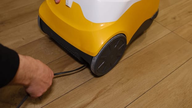 Caucasian man packing cable of the vacuum cleaner inside the storage in it. Angry Man trying to pack sticked cable in vacuum cleaner