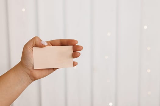 Female hand holding blank card. Woman hand holding empty business card, credit card or blank paper. Mockup design template.