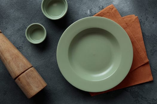 Green empty plate, cutlery and napkin on stone table top view. Table setting mock up. Vertical