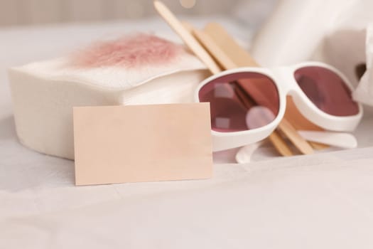 Safety glasses, UV protection. Empty business card, credit card or blank paper. Many wax wooden spatulas. The concept of beauty, depilation, waxing, sugaring smooth skin without hair, banner, health.