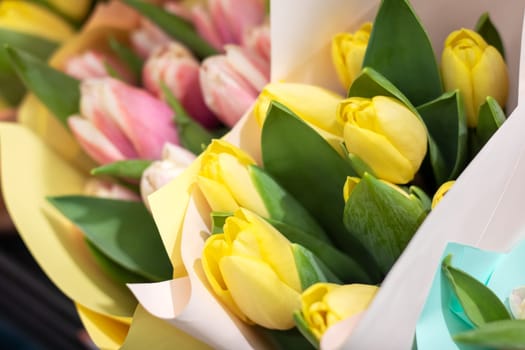 A beautiful bouquet of pink and yellow flowers, wrapped in paper. The vibrant colors of the petals make it perfect for flower arranging or as a natural ingredient in cooking