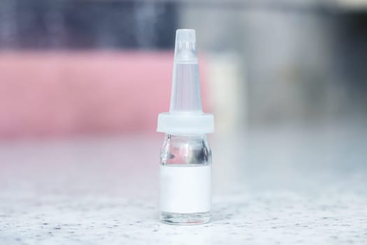 A small glass bottle of electric blue liquid nasal spray is displayed on a counter, resembling a futuristic gadget. Perfect for macro photography or as an automotive lighting solvent