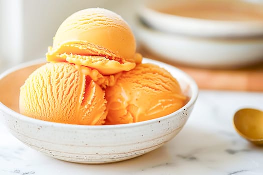 Balls of delicious mango ice cream lie in a white bowl on a table with a marble surface.