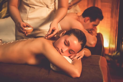 Couple customer having exfoliation treatment in luxury spa salon with warmth candle light ambient. Salt scrub beauty treatment in Health spa body scrub. Quiescent