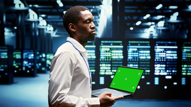 Engineer using green screen laptop to do maintenance on high bandwidth, dedicated game servers used to accommodate incoming traffic of online users joining from worldwide locations.