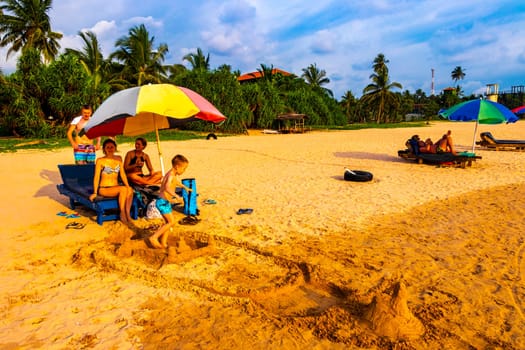 Beautiful beach with tropical nature sand water waves people fun parasols and sun loungers in Bentota Beach on Sri Lanka island.