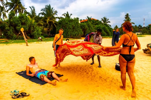 Beautiful beach with tropical nature sand water waves people fun parasols and sun loungers in Bentota Beach on Sri Lanka island.