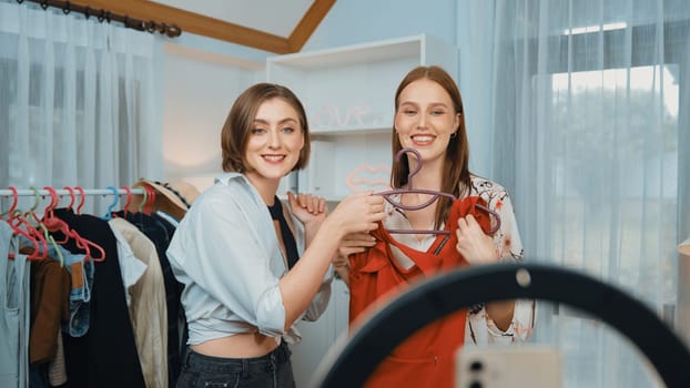 Two women influencer shoot live streaming vlog video review clothes prim social media or blog. Happy young girl with apparel studio lighting for marketing recording session broadcasting online.