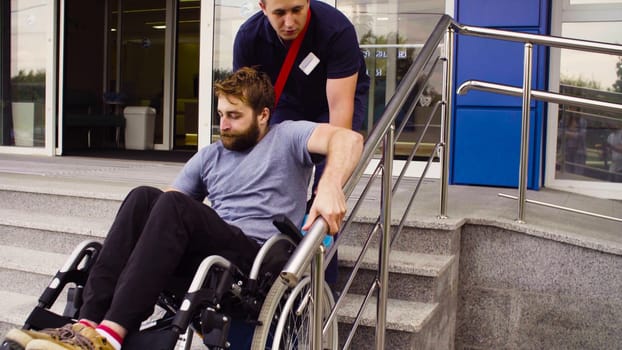A man helping to move down the stairs to a disabled person in a wheelchair