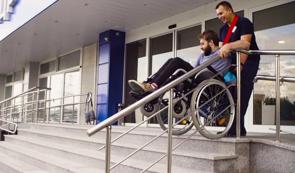 A man helping to move down the stairs to a disabled person in a wheelchair