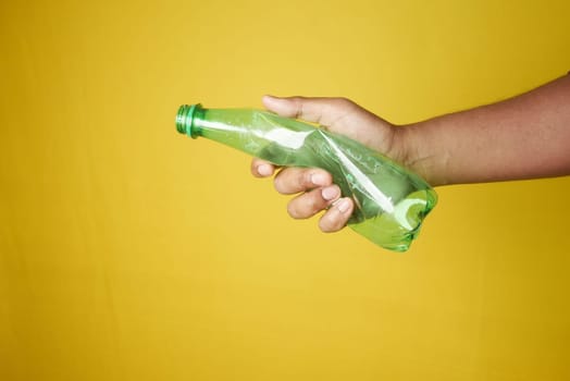A person is grasping a plastic bottle with their fingers and thumb.