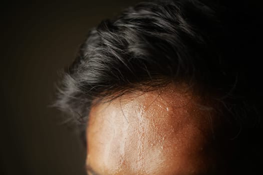 closeup of sweat on forehead against dark background