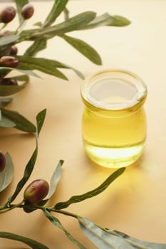 bottle of olive oil and olive leaves on yellow ,