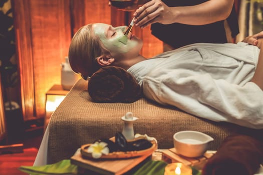 Serene ambiance of spa salon, woman customer indulges in rejuvenating with luxurious face cream massage with warm lighting candle. Facial skin treatment and beauty care concept. Quiescent