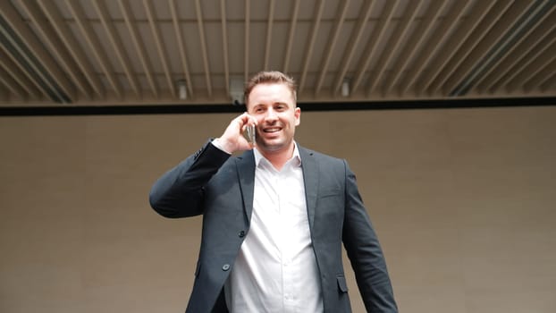 Skilled businessman calling his colleague to plan financial strategy while walking to workplace. Project manager using mobile phone to communicate with team while talking to phone. Lifestyle. Urbane.