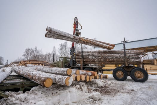 Sawmill in wintertime. Image of truck loading timber