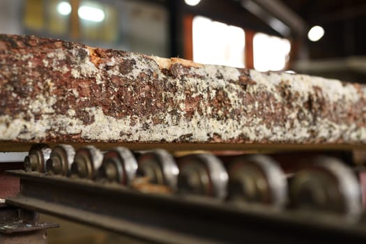 Woodworking process. Close-up of wooden bar with bark