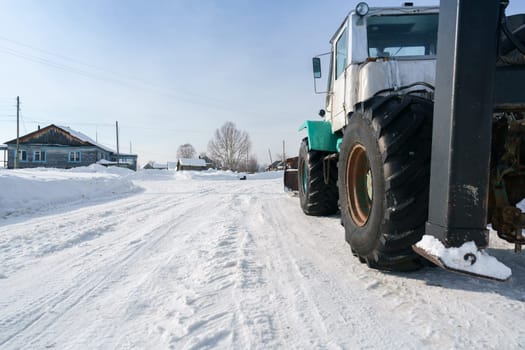 Tractor rides through village in winter, close-up