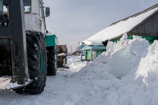 Winter time. Tractor cleans snow in village, close-up
