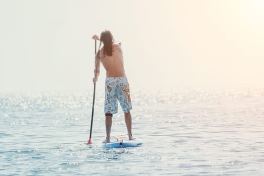 Man Sea Sup. Strong athletic man learns to paddle sup standing on board in open sea ocean on sunny day. Summer holiday vacation and travel concept. Aerial view. Slow motion.
